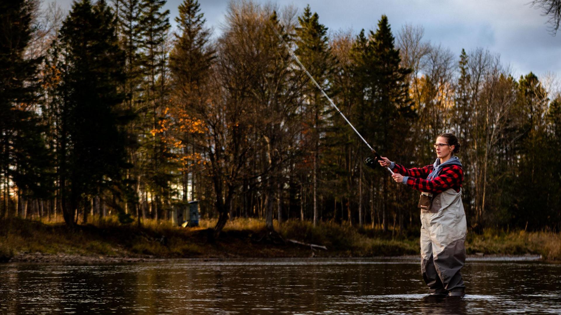 A person in plaid and waiters fishing on the Escanaba river