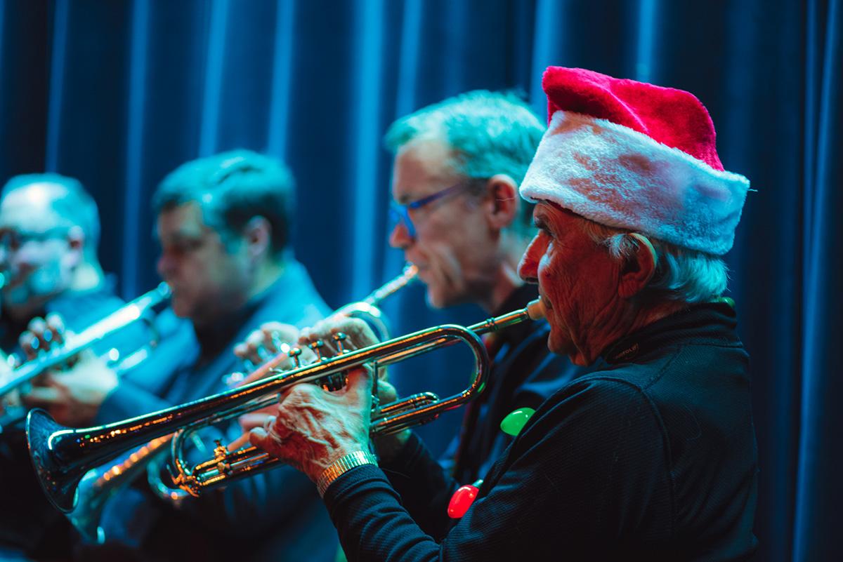 4 people playing the trumpet with one wearing a santa hat