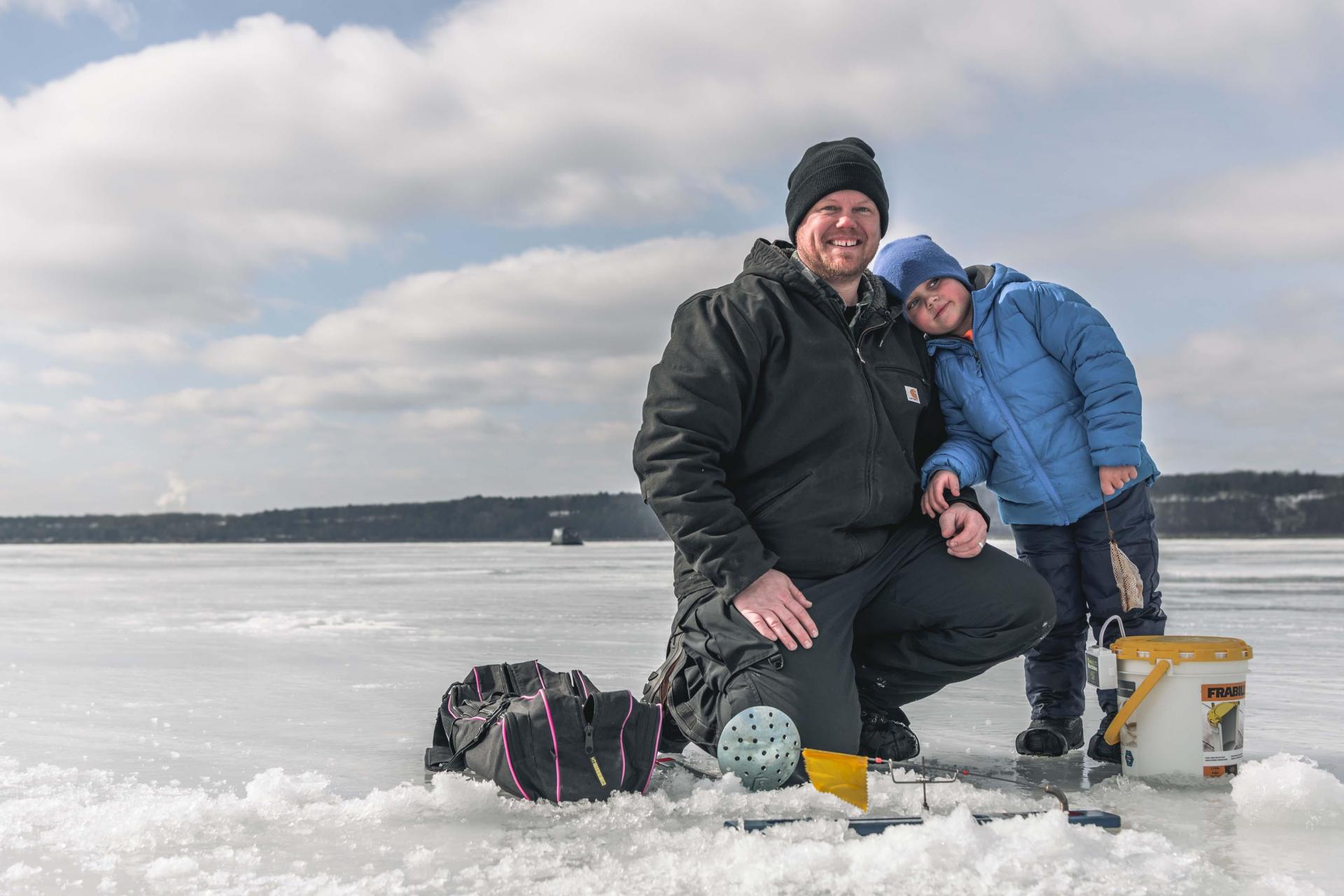 An adult and child ice fishing.