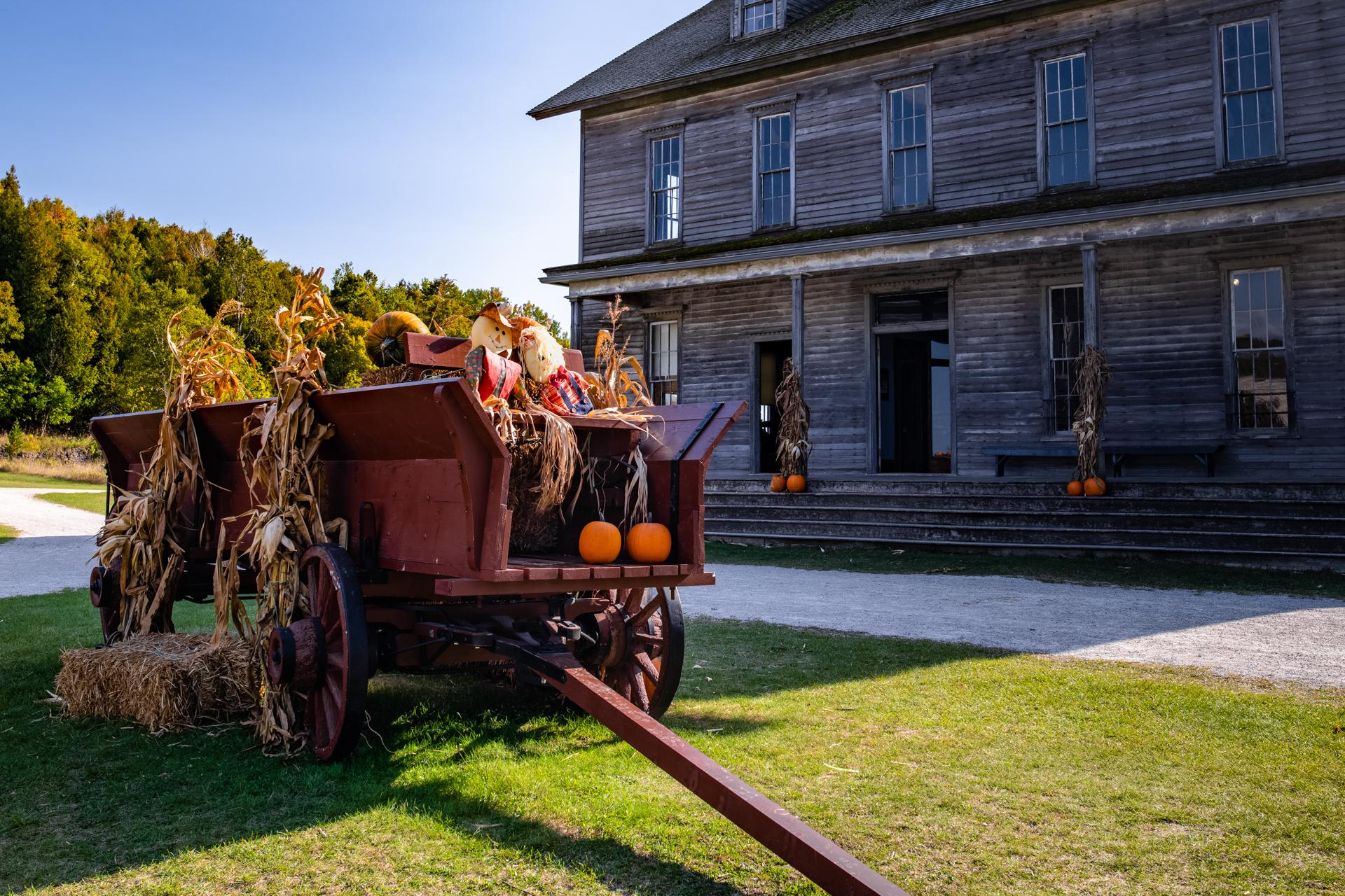 a wagon filled with hay, pumpkins and scarecrows