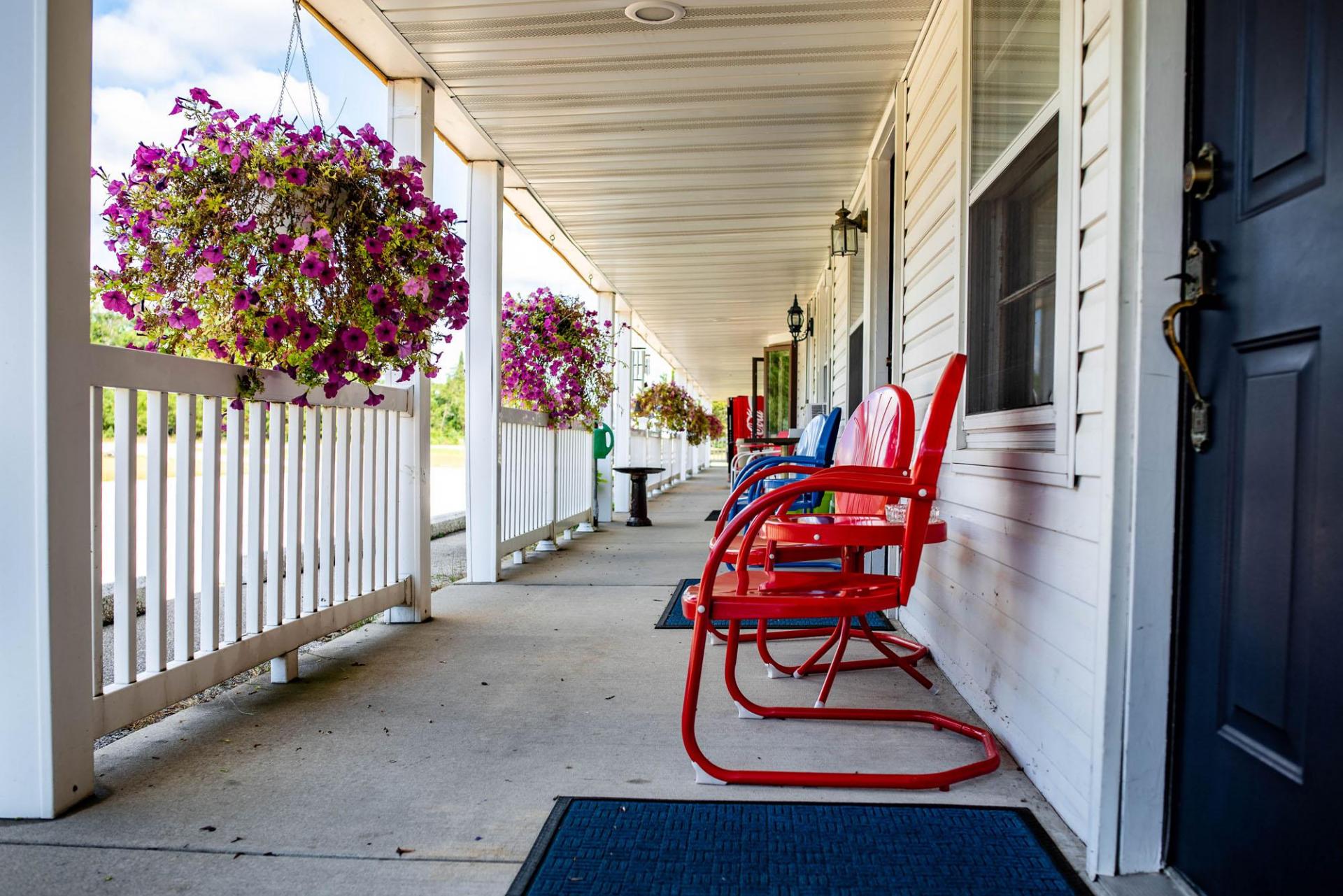 Chair on a porch and hanging flower baskets.
