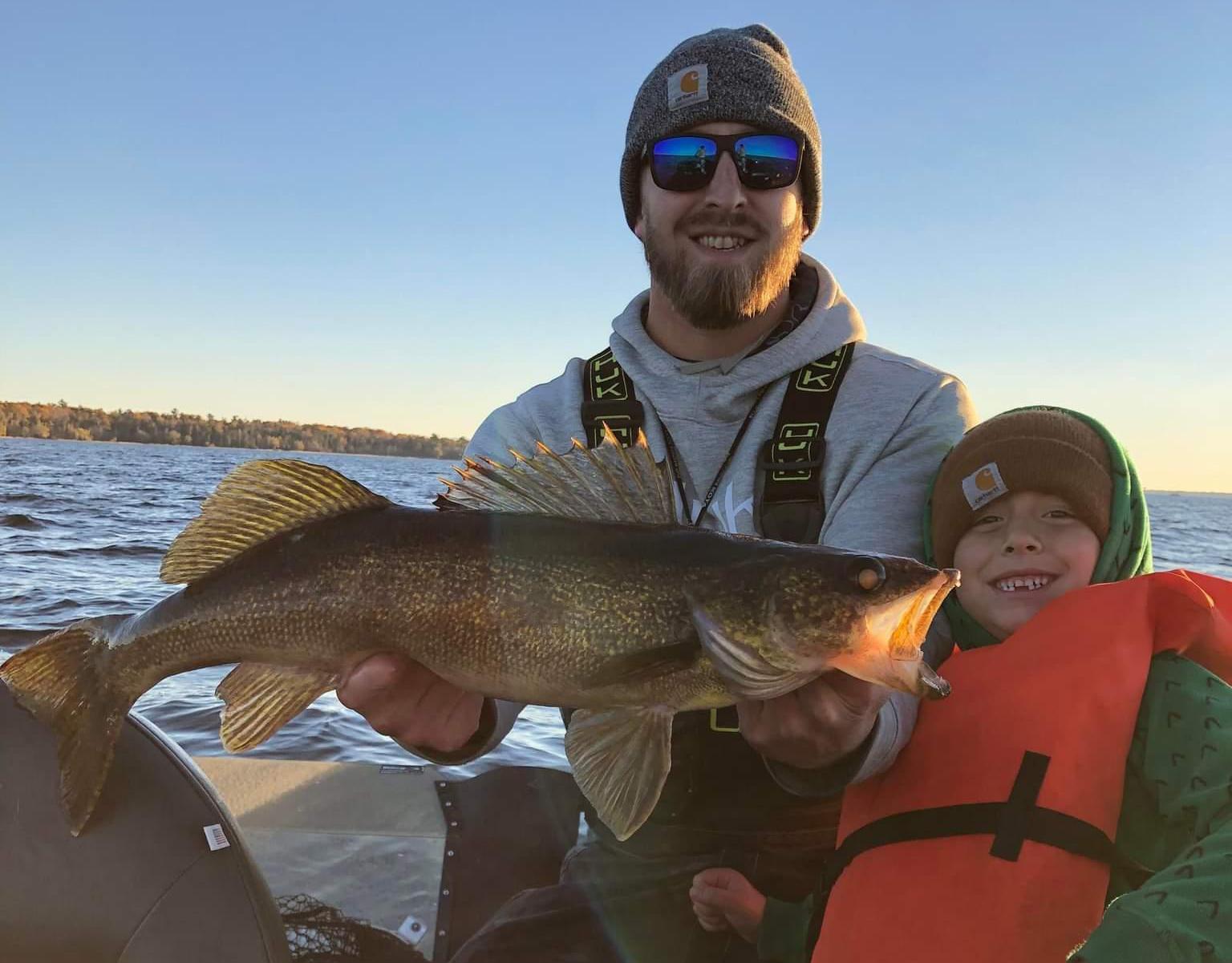 A father and son posing with a large walleye. 