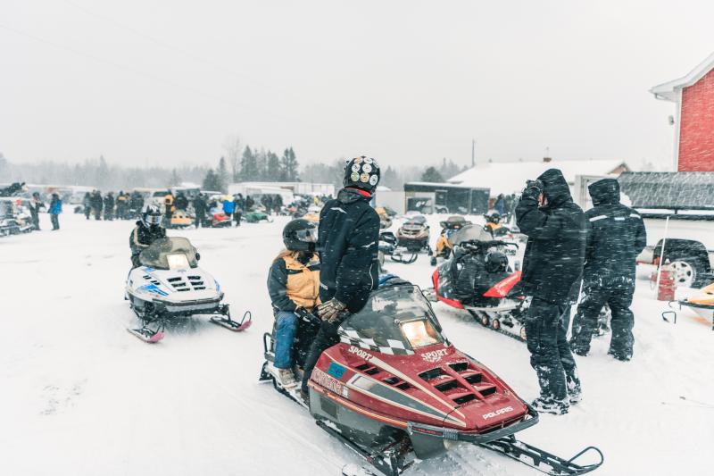 A group of snowmobilers preparing for a ride.
