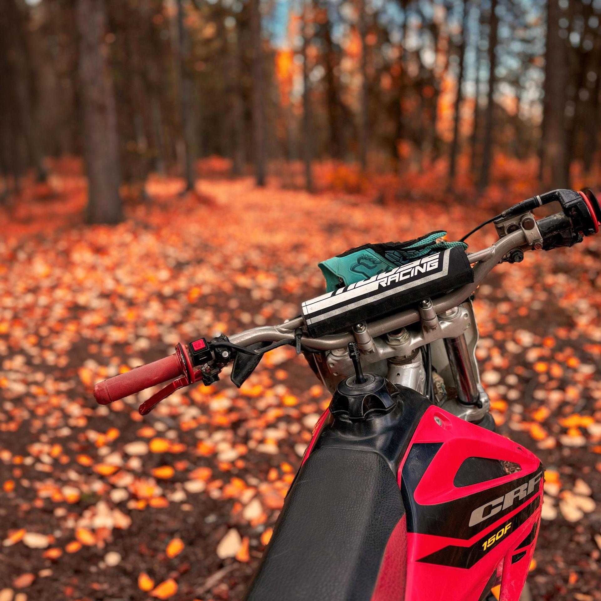 An off-road motorcycle parked beside a scenic trail surrounded by autumn colors.