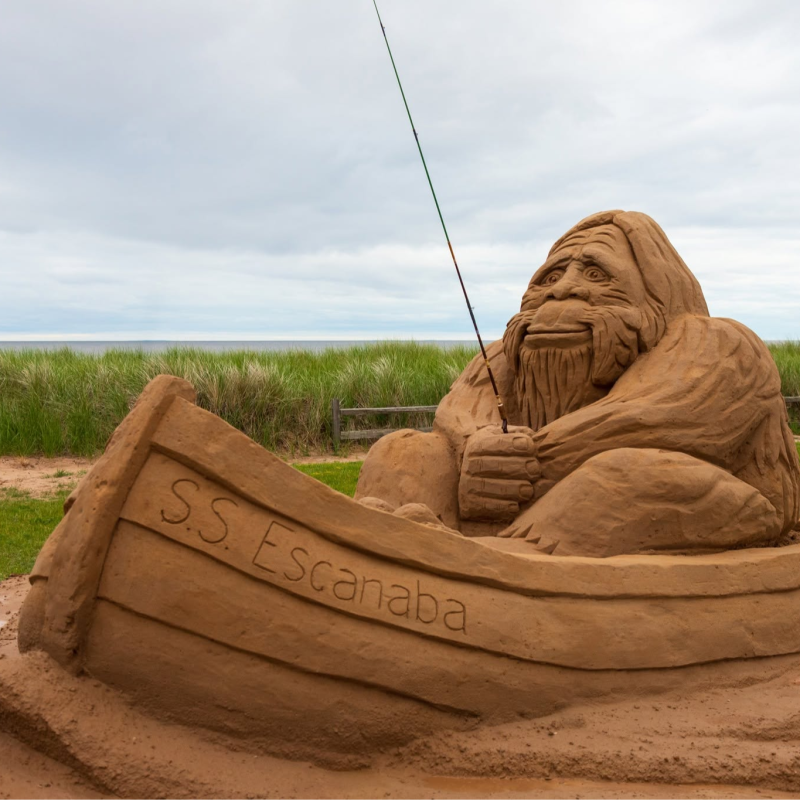 A detailed sand sculpture depicting Bigfoot fishing in a boat.