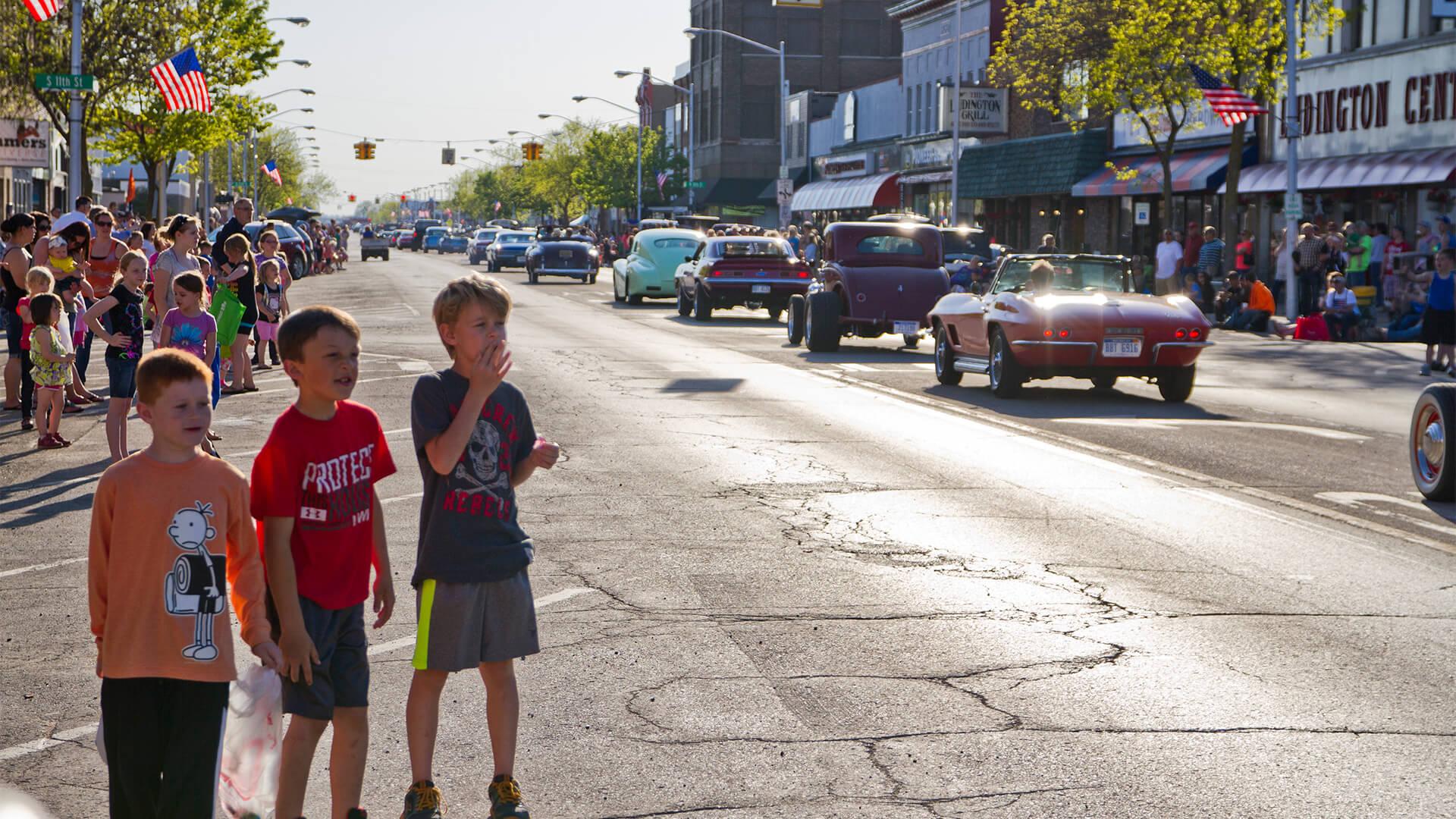 boys watching a parade of old cars