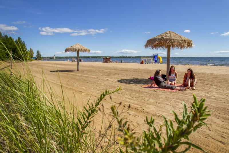 three girls sitting under an umbrella at the beach