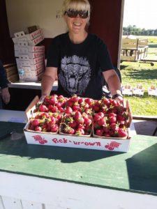 woman holding a palette of fresh strawberries