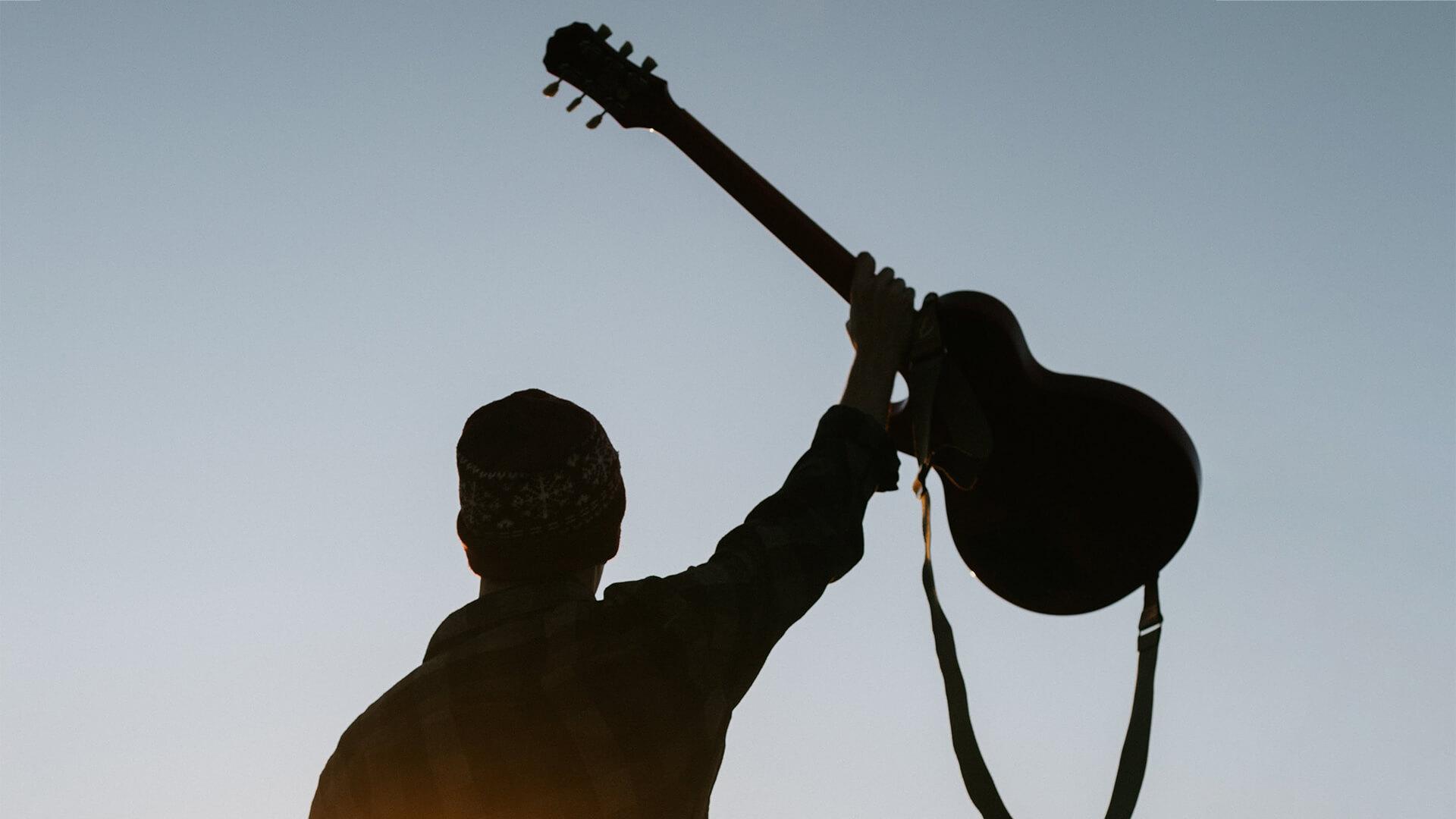 silhouette of man holding guitar
