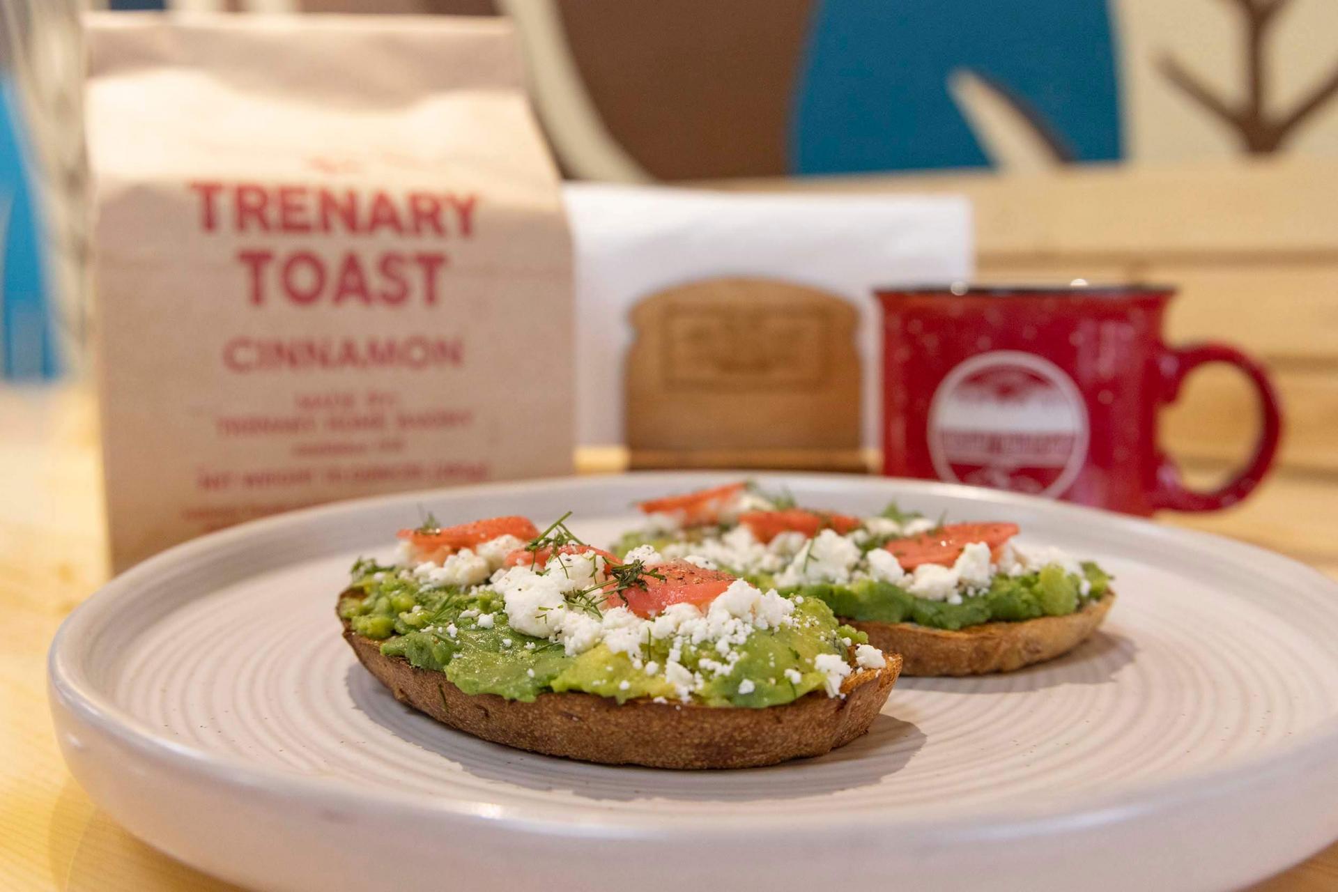 A plate of two pieces of avocado toast on homemade Trenary toast.