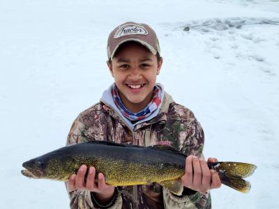 Young boy holding up his ice fishing catch.
