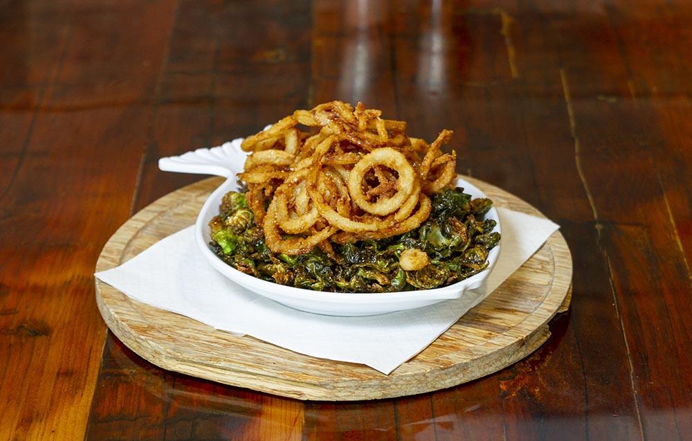A plate of brussel sprouts and fried onion strings.