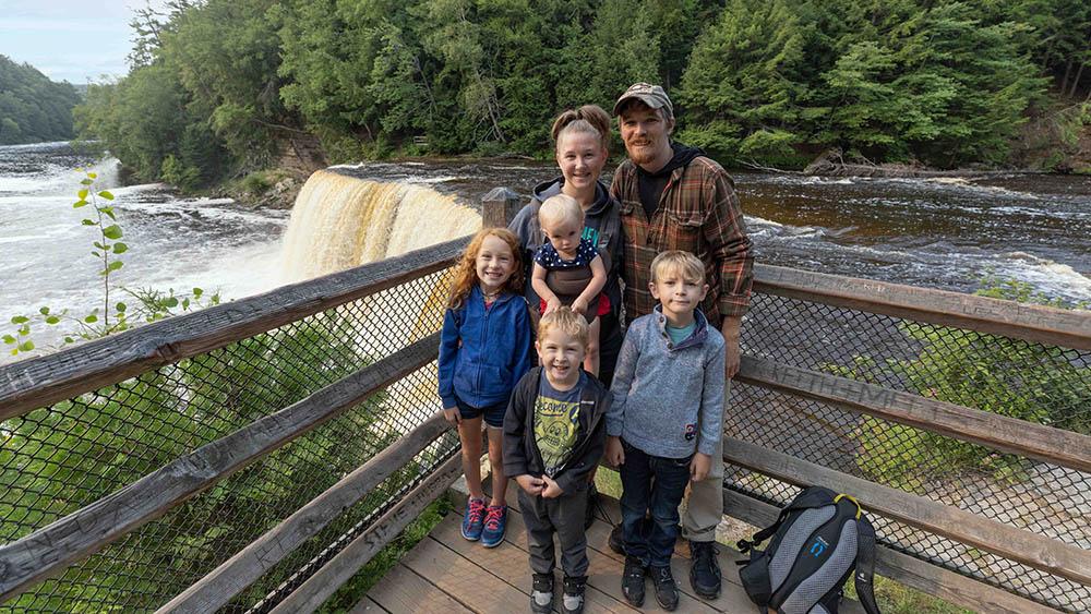 A family posing in front of Upper Tahquamenon Falls.